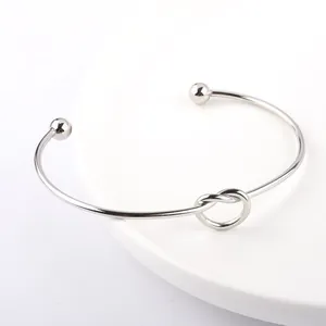 Detailed macro view of minimalist heart knot design on a silver titanium steel cuff bracelet