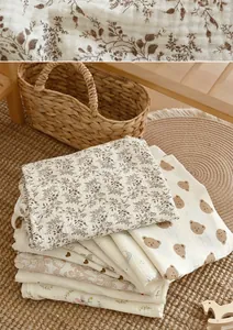 Close-up view of stacked soft cotton muslin nursing covers with floral and bear prints.