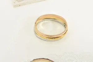 Close-up of three titanium steel bangles in gold, rose gold, and silver with rhinestones.