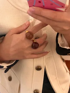 Close-up detail of vintage chocolate and caramel enamel egg-shell rings worn on a hand
