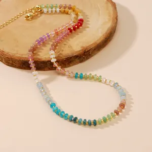 Collier de perles colorées en pierres semi-précieuses avec touches dorées sur support bois