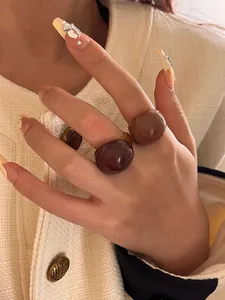 Close-up of glossy chocolate and caramel enamel eggshell open rings on a hand model