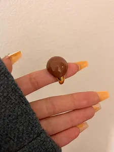 Detailed close-up of retro chocolate caramel round enamel eggshell ring on hand