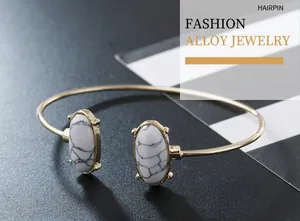 Close-up of a gold-toned open cuff bracelet featuring two elegant oval white marble stones.