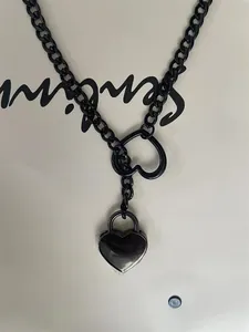 Punk style black chain necklace featuring heart toggle and heart padlock pendant detail