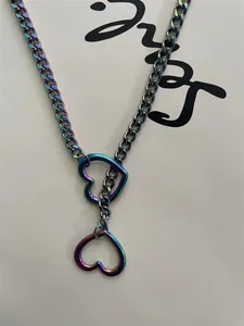 Detail of iridescent heart pendant necklace with punk style Cuban chain design.