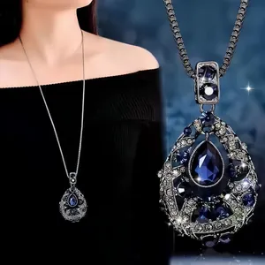 Detailed view of teardrop pendant necklace featuring deep blue and white crystals.