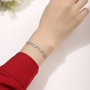 Close-up of a silver 'LOVE' letter bracelet with moissanite on a woman's wrist