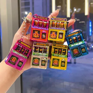 Detailed view of multiple colorful electroplated mini slot machine keychains held in hand