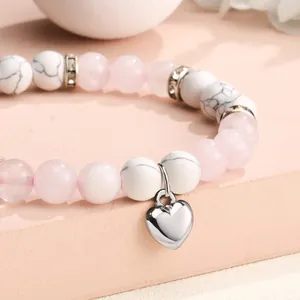 Macro detail view of pink quartz and white turquoise beaded bracelet with heart charm