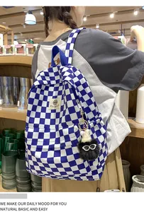 Detailed shot of a blue and white checkered backpack featuring a cute black fuzzy charm