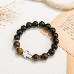 Close-up of natural tiger's eye and black obsidian beaded bracelet with white cross