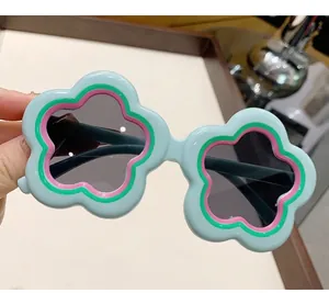 Close-up of children's flower-shaped sunglasses with green frames and gray lenses
