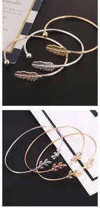 Detailed macro view of minimalist gold and silver feather and leaf motif open bangles