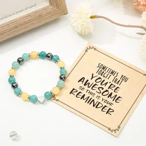 Close-up of beaded heart bracelet with motivational message card and white flower detail