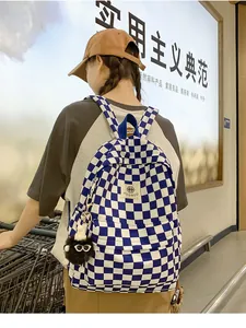 Blue and white checkerboard school bag with a cute furry keychain charm on a model