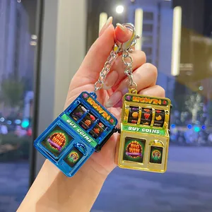 Close-up detail of blue and gold electroplated mini slot machine keychains in hand