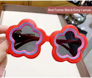 Close-up of children's red flower-shaped sunglasses with protective dark grey lenses.