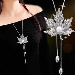 Detailed macro view of a silver maple leaf sweater necklace with pearl and sparkling crystals