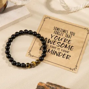 Detailed view of black matte beaded bracelet with tiger eye accents and gift card.