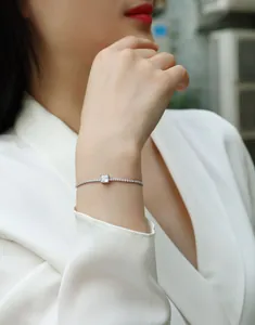 Elegant sterling silver tennis bracelet with a square moissanite stone on a female wrist.
