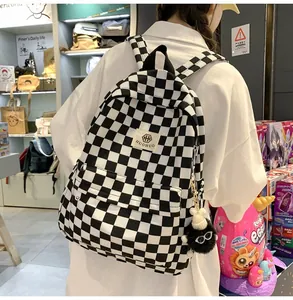 Back view of a retro black and white checkered canvas backpack worn by a student