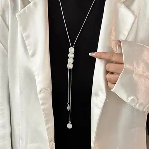 Detail view of elegant titanium steel long necklace with white cat eye stones on model.