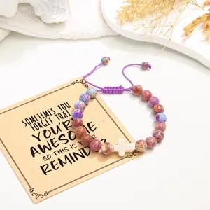 Close-up view of a purple imperial jasper beaded cross bracelet paired with a gift card