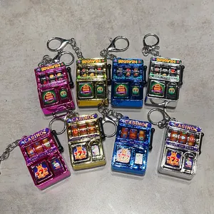 Detail view of colorful electroplated mini slot machine keychains in pink, gold, and blue.