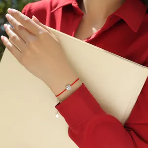 Close-up of heart-shaped moissanite charm on a delicate red string bracelet worn by a model