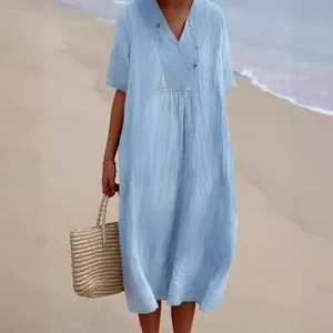 Abito midi rilassato in cotone e lino azzurro mostrato in spiaggia con borsa intrecciata