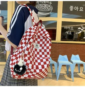 Detail view of red and white checkered retro backpack with cute monster charm