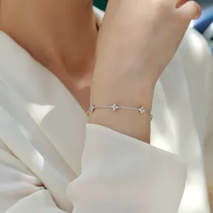 Elegant sterling silver bracelet featuring moissanite flower charms on a model wrist