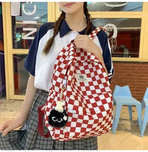 Red and white checkered backpack for students with a cute black monster keychain detail.