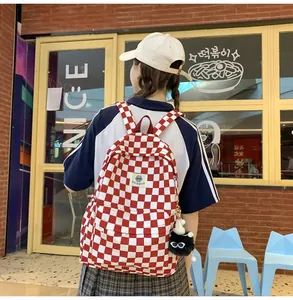 Model wearing a retro red and white checkered backpack in a casual street setting.