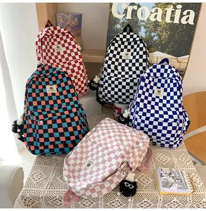 Multi-color checkered school backpacks with plush charms on elegant lace background