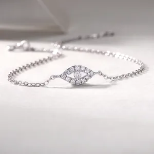 Detailed macro view of a silver eye charm bracelet with sparkling stones on soft fabric.