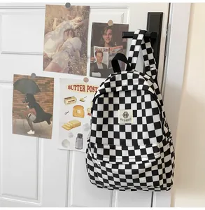 Retro black and white checkered canvas backpack with adjustable straps and front storage pocket.