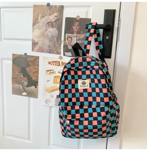 Detailed close-up of a retro teal and peach checkered schoolbag hanging on a white door