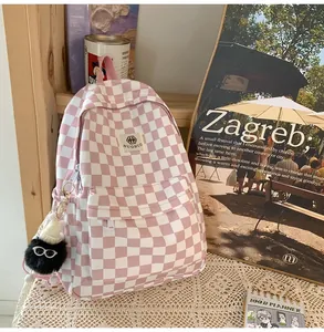 Pink checkered vintage backpack with cute black pom-pom charm in lifestyle setting