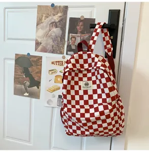 Detail view of a retro red and white checkerboard backpack hanging on a white door handle