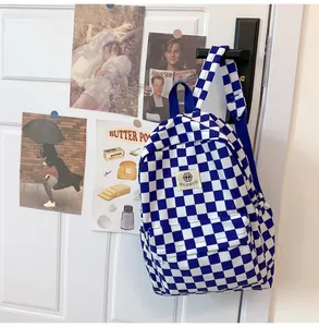 Detailed view of a retro blue and white checkered backpack hanging on a white door.
