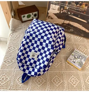 Detailed view of a blue and white checkered backpack on a white lace tablecloth