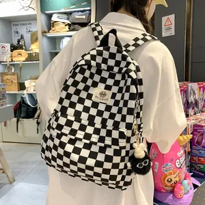 Stylish retro black and white checkered student backpack featuring a cute fuzzy charm pendant