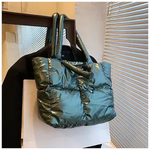 Close-up detail of metallic dark green padded tote bag with quilted down jacket texture.