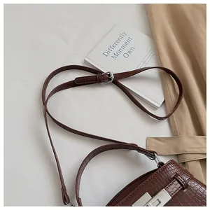 Detail view of brown croc-embossed Kelly bag with adjustable shoulder strap