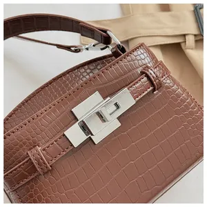 Close-up of brown crocodile pattern handbag with silver Kelly style lock detail