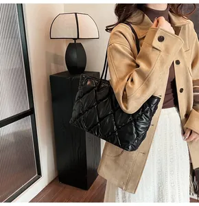 Detailed view of a stylish black quilted puffer tote bag carried by a model in a winter outfit.