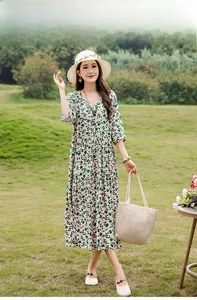 Beautiful woman wearing green leaf print cotton silk midi dress in a lush garden