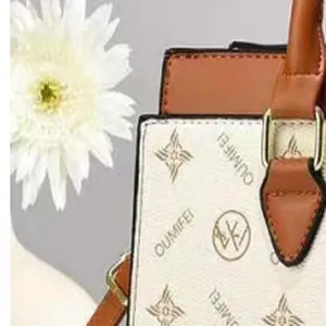 Close-up of OUMIFEI patterned leather handbag with elegant white flower background